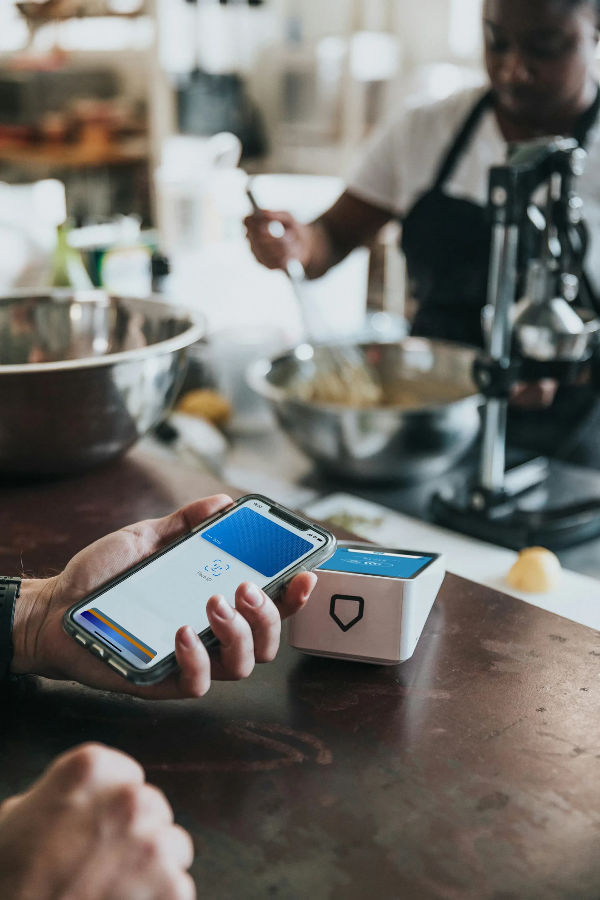 A customer tapping their phone against a Pocket payment terminal at a café counter